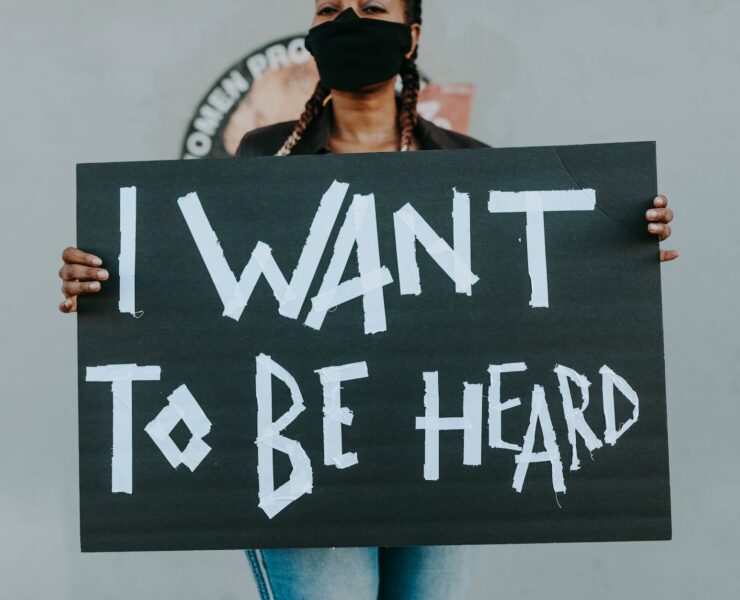 woman with face mask holding a sign