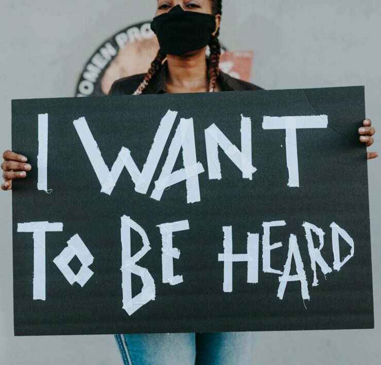 woman with face mask holding a sign